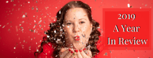 A photo of Erica Steeves blowing gold and silver glitter towards the camera wearing a red blouse on a red background