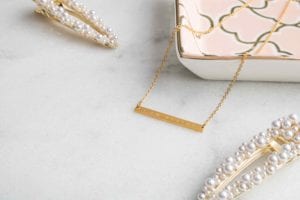 Product Photography Gold I Am Worthy necklace by Jenna Kutcher lifestyle image on marble back ground