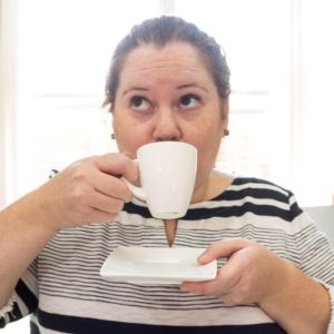 Erica Steeves drinking a cup of tea in a black and white striped shirt. 