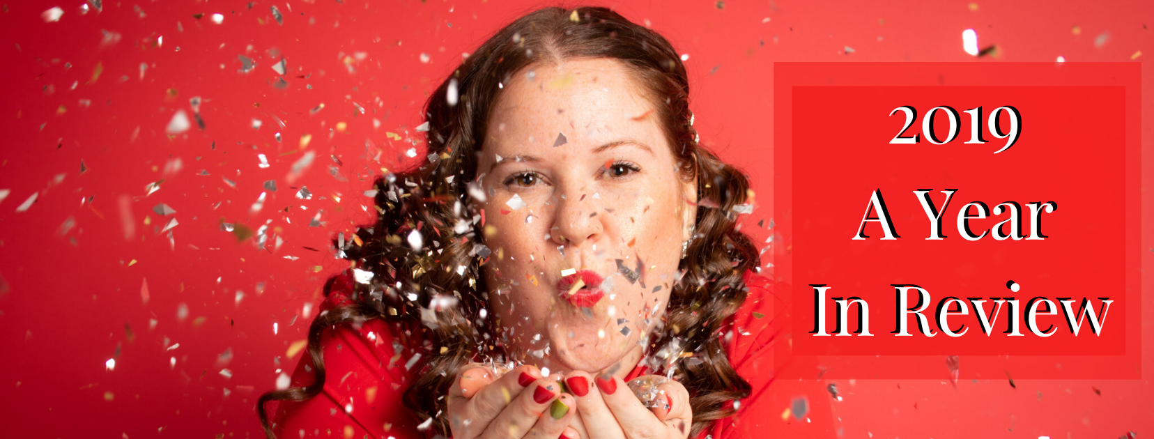 A photo of Erica Steeves blowing gold and silver glitter towards the camera wearing a red blouse on a red background